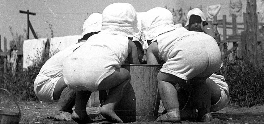 toddlers getting water out of a bucket