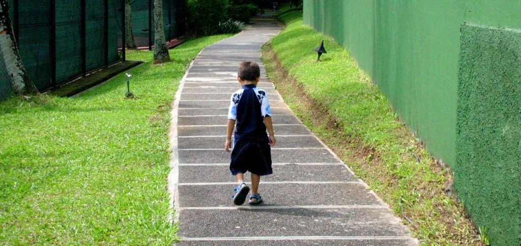 Boy walking down the sidewalk alone