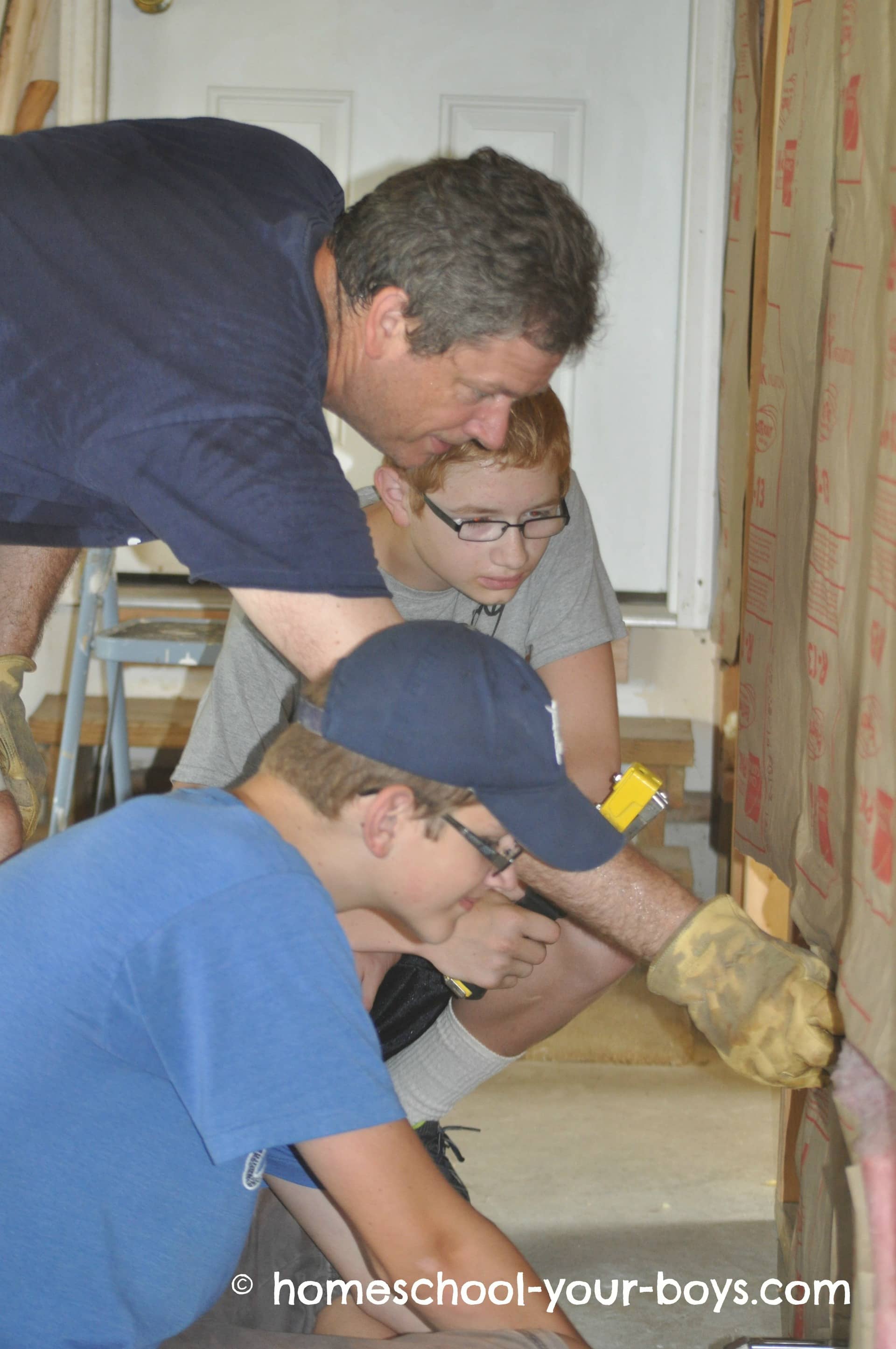 Dad showing his sons how to hang insulation